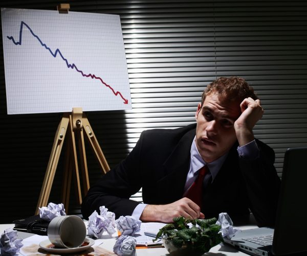 Businessman frowning with crumpled paper balls on the table