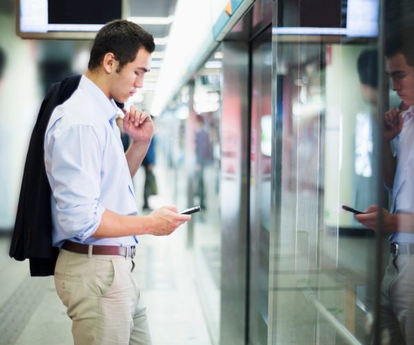 Businessman looking at his phone and waiting for the subway in Beijing